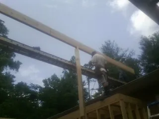 Carpenter setting a ridge beam over a new addition frame — Ice Dam Removal by Roofing Brothers in Winnett