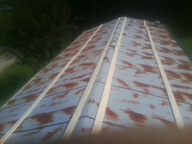 Rusted metal roof panels with new wood purlins before replacement — Storm Damage Roof Repair in Winnett by Roofing Brothers