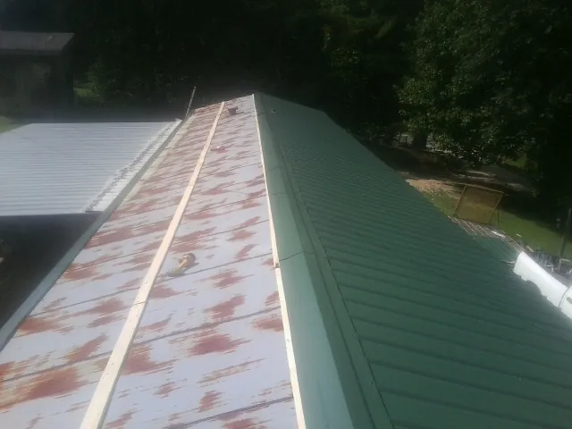Old rusted panels beside newly installed green metal roofing — Wind Damage Roof Repair by Roofing Brothers in Winnett