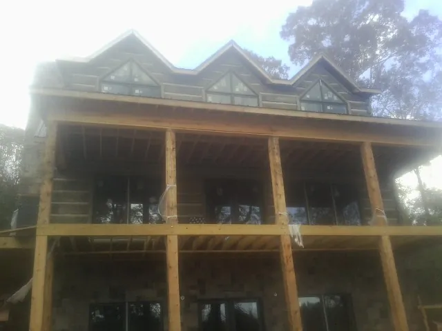 Dormers and porch framing on a large log home under construction — Roof Coating work by our crew in Winnett