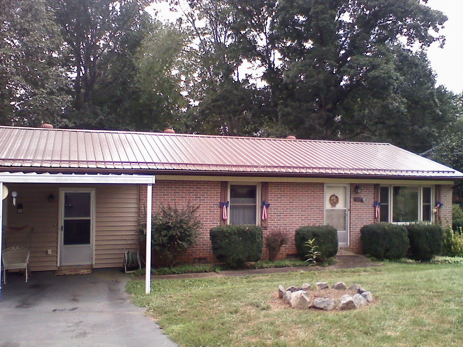 Bronze metal roof and carport on a brick ranch home — Roof Repair work by our crew in Winnett