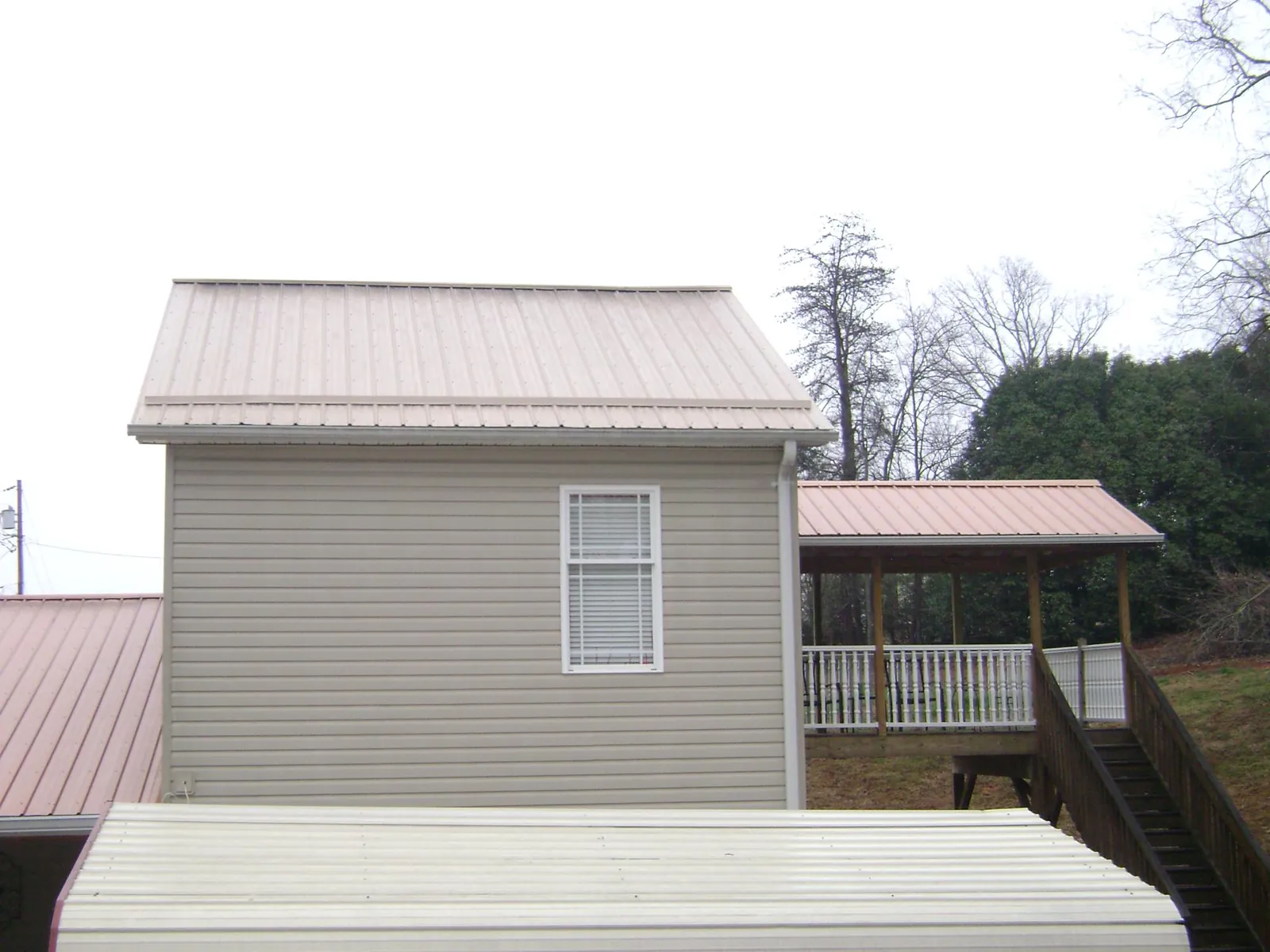 Tan metal roofs on a two story addition and attached porch, from a Roof Replacement job in Winnett