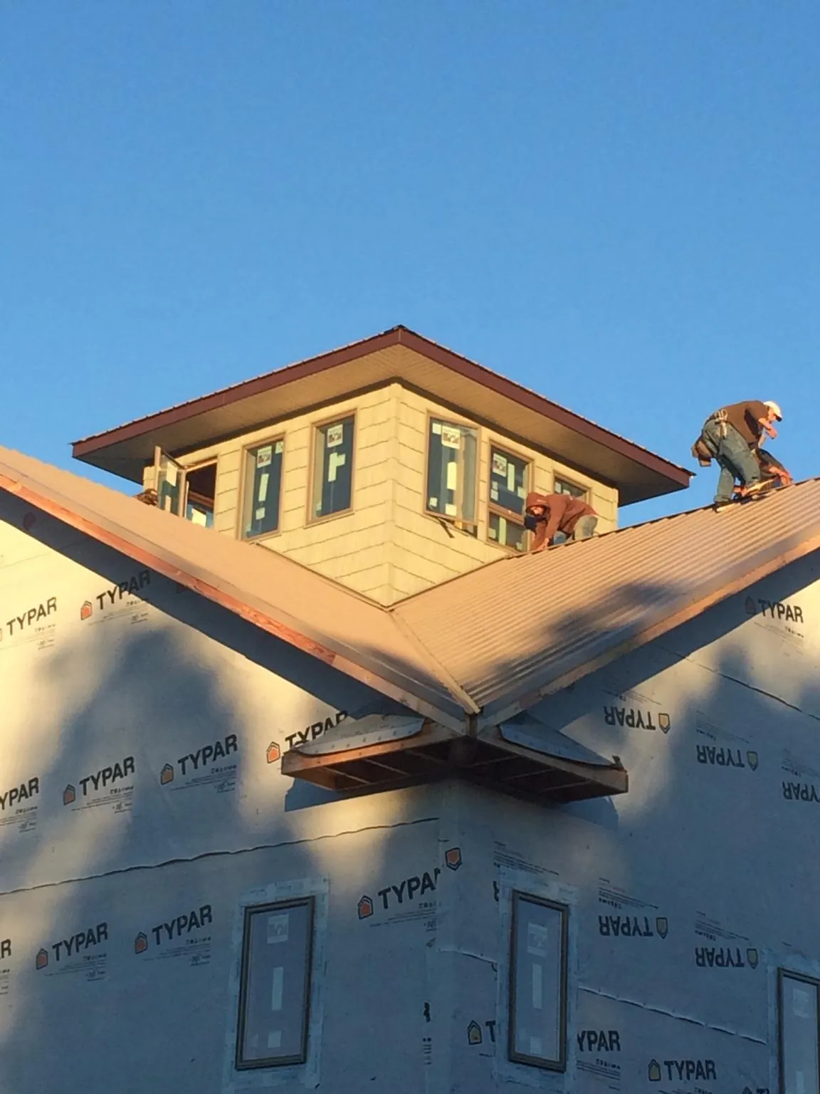 Roofers working around a rooftop cupola on a new metal roof at sunset — Roof Waterproofing in Winnett by Roofing Brothers